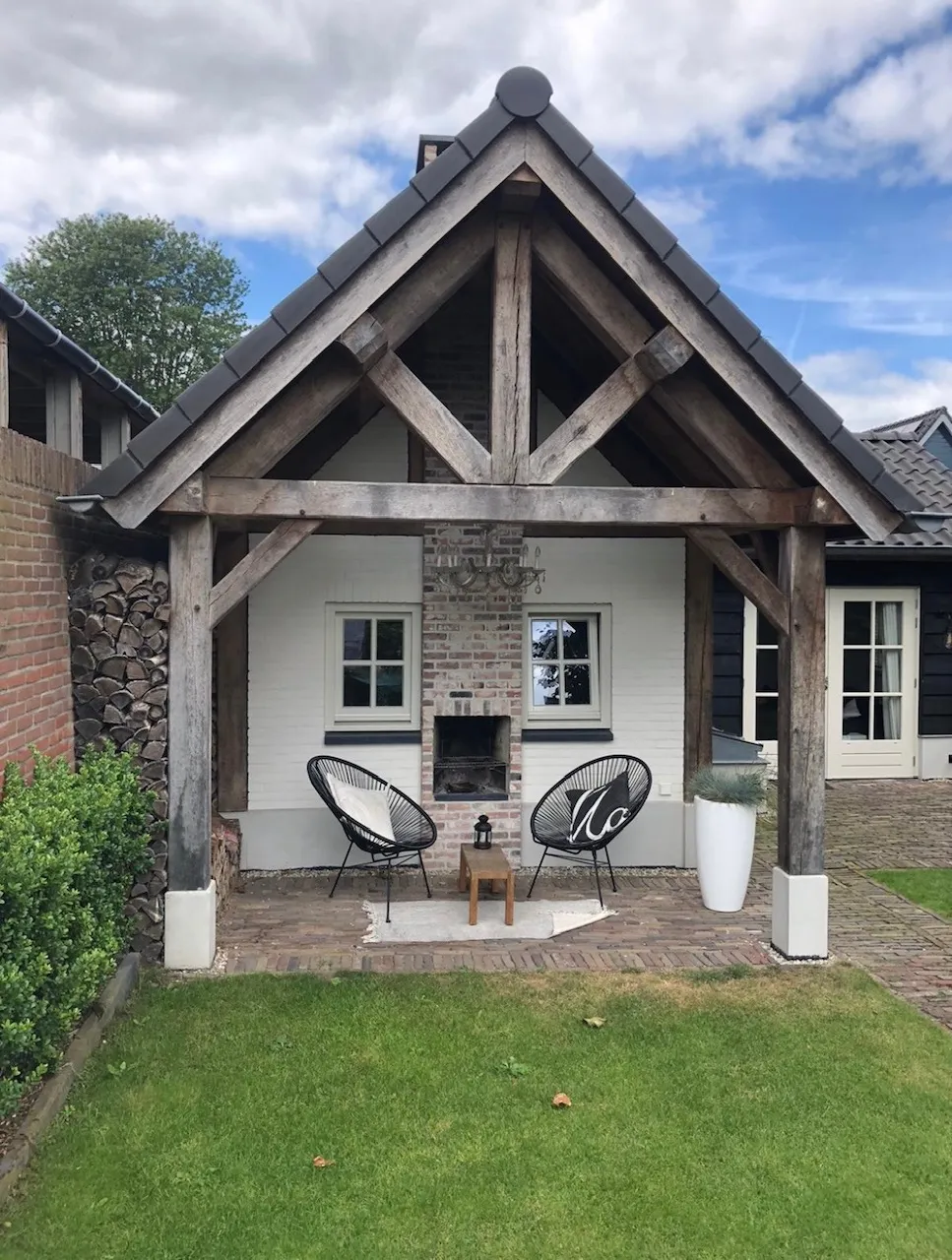 Landelijk pand met een houten overkapping en wit geschilderd metselwerk.