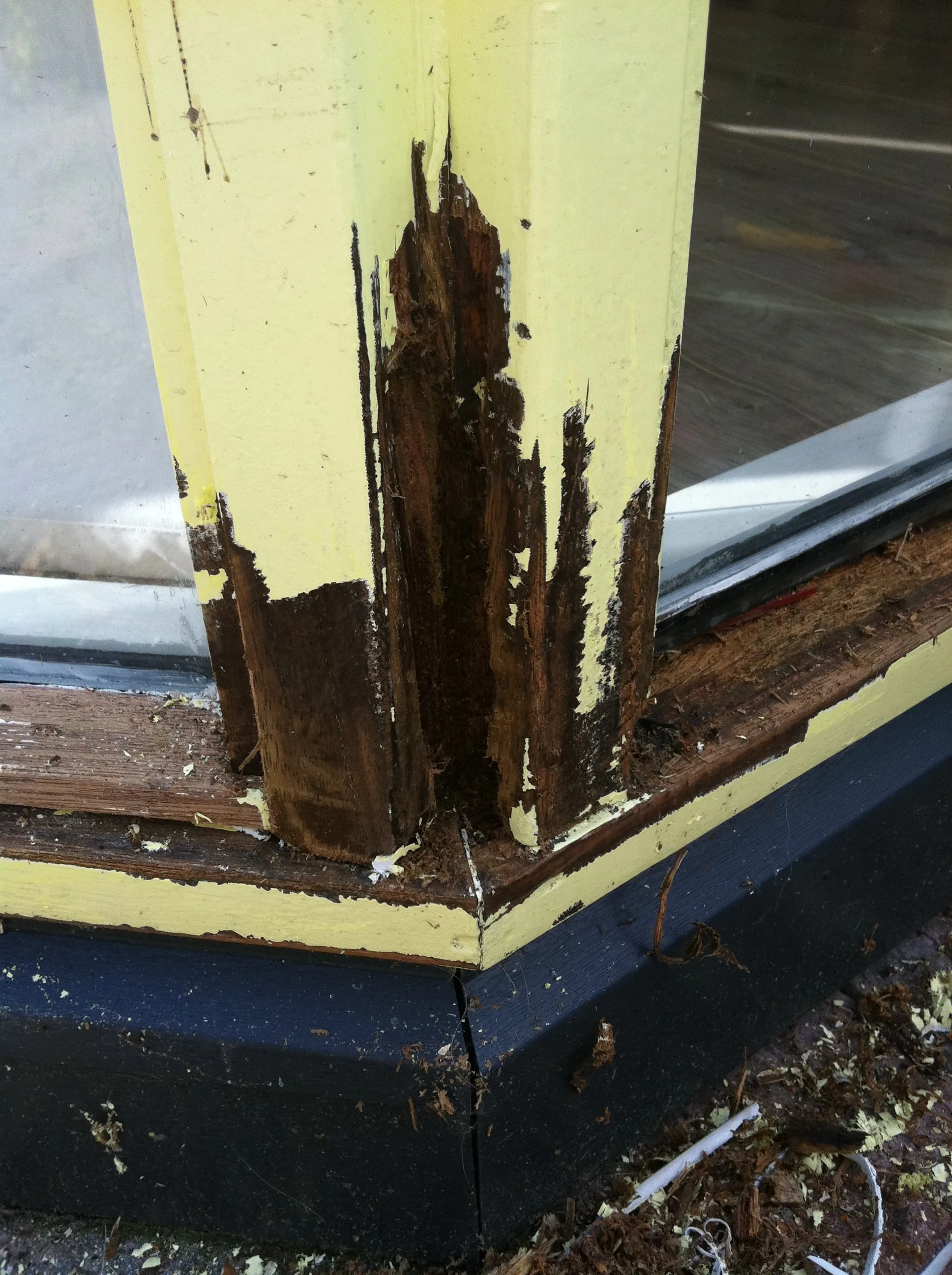 Houtrot blootgelegd in de hoek van een kozijn: het aangetaste hout is duidelijk zichtbaar.