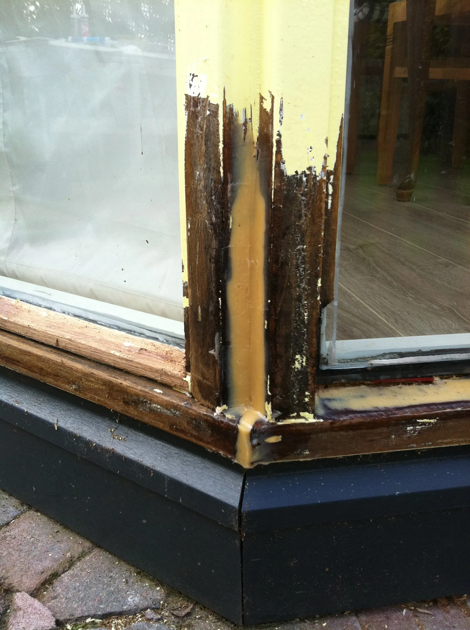 Dezelfde kozijnhoek tijdens het herstel: het rotte hout is verwijderd en opgebouwd met epoxy.