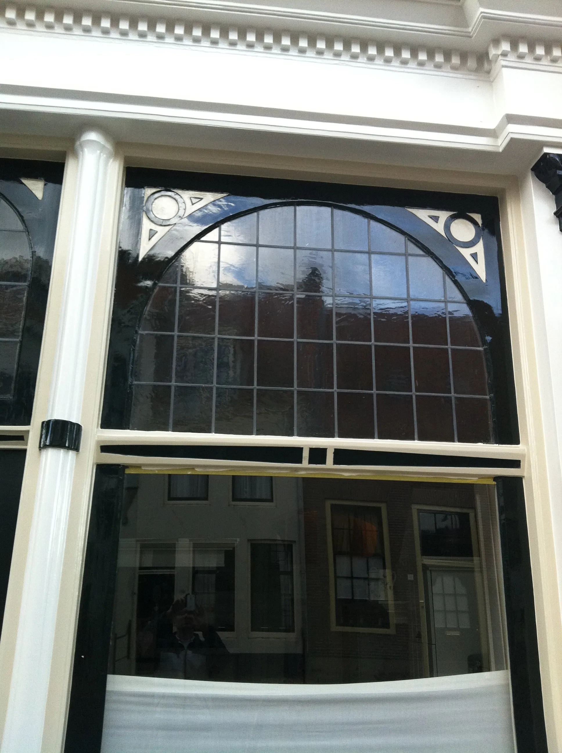 Herstelde winkelpui met glas-in-loodbovenlicht, strak in de zwarte lak.