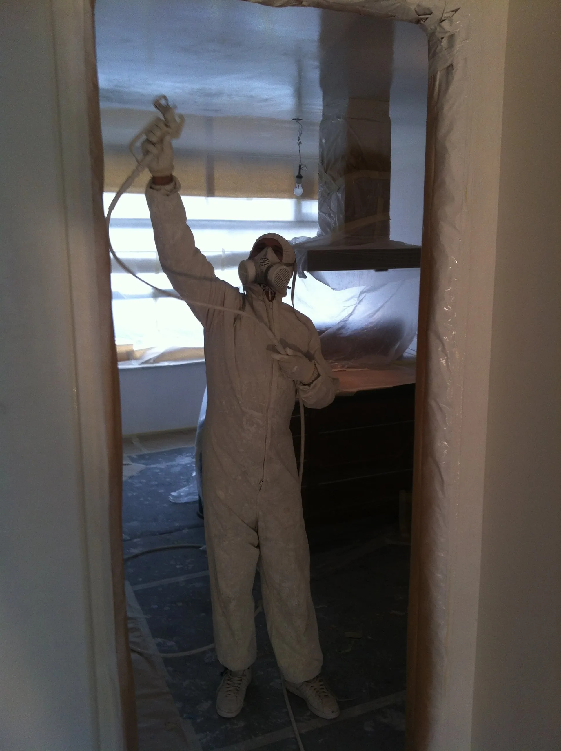 Gespoten plafond in een ruime woonkamer; kozijnen en radiator nog afgeplakt.