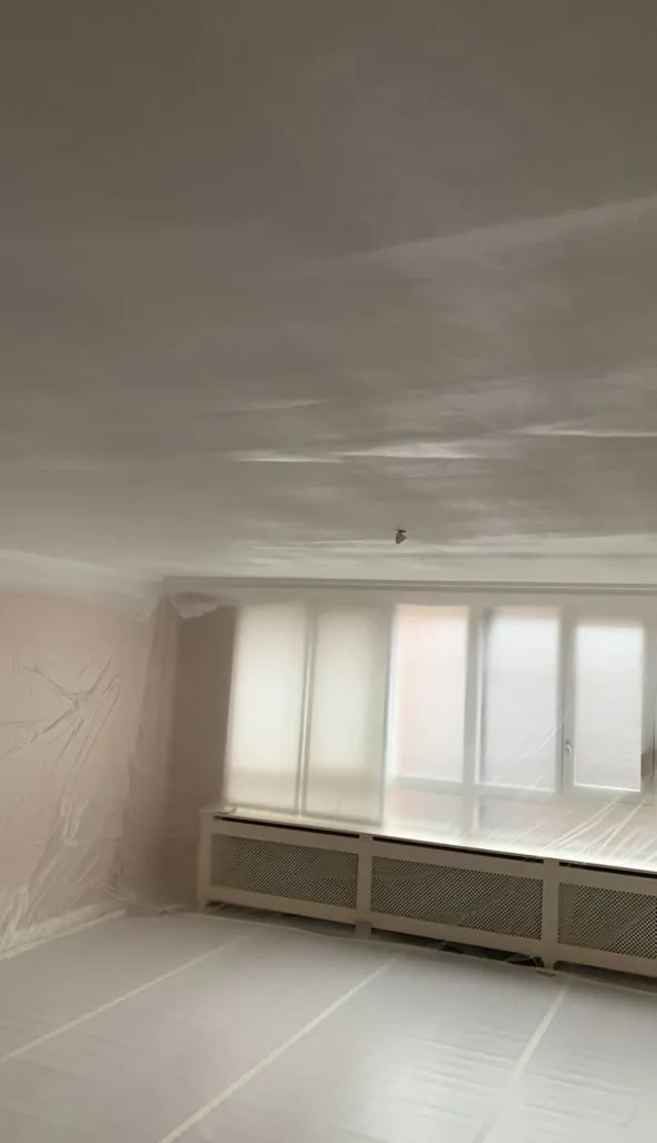 Dave spuit het plafond, met adembescherming en in beschermende kleding.